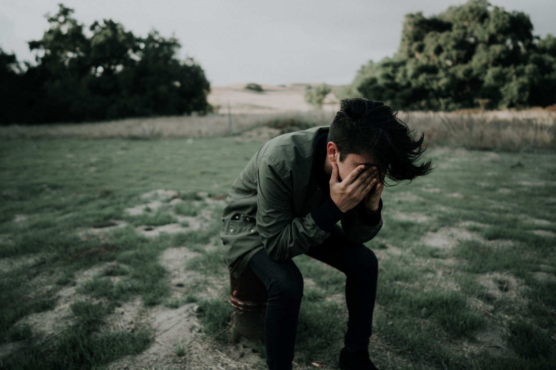 Man sitting outdoors with his hands on his forehead