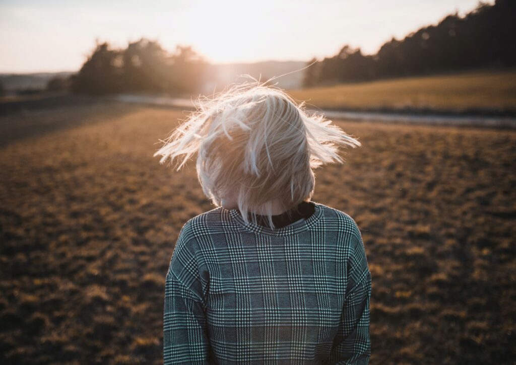 Girl shaking head while standing in a field