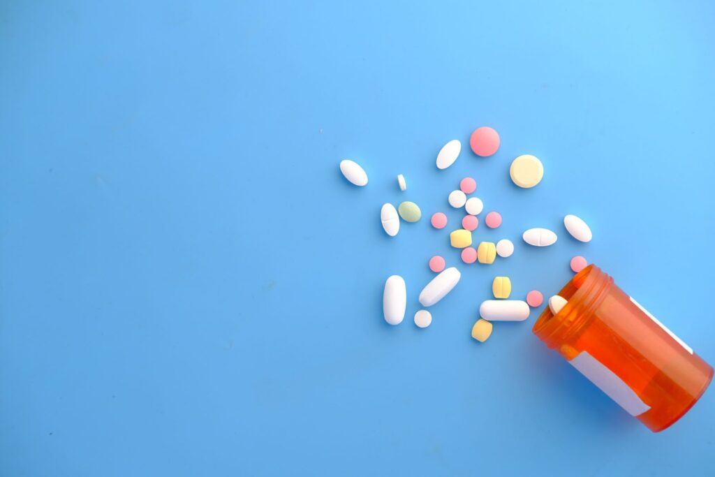 Different pills laying on a table with a pill bottle