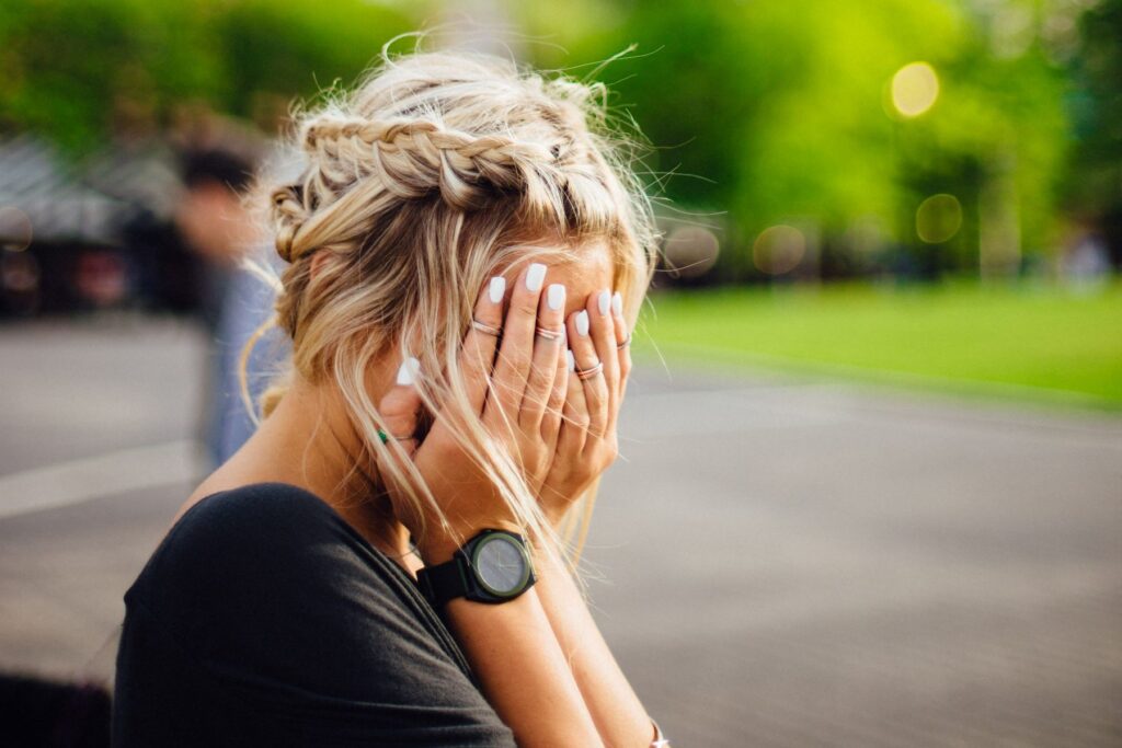 Lady sitting on bench with her hands over her face